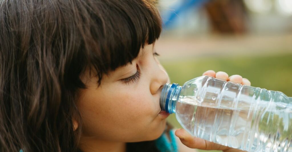 Una bambina che beve acqua da una bottiglietta