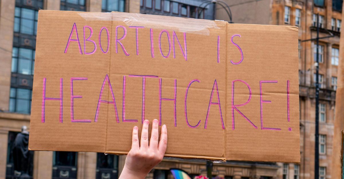 Primo piano di un cartello di protesta in cartone con la scritta "ABORTION IS HEALTHCARE!" (L'aborto è assistenza sanitaria)