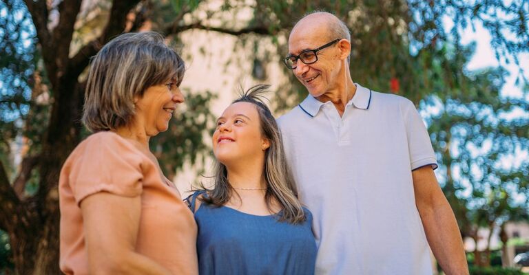 Coppia di genitori non giovanissimi felice all'aperto con figlia con sindrome di Down