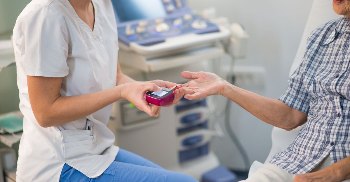 Un operatore sanitario in divisa esegue un test della glicemia a un paziente anziano seduto in uno studio medico