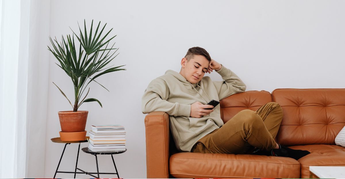 ragazzo sdraiato sul divano, guarda il cellulare