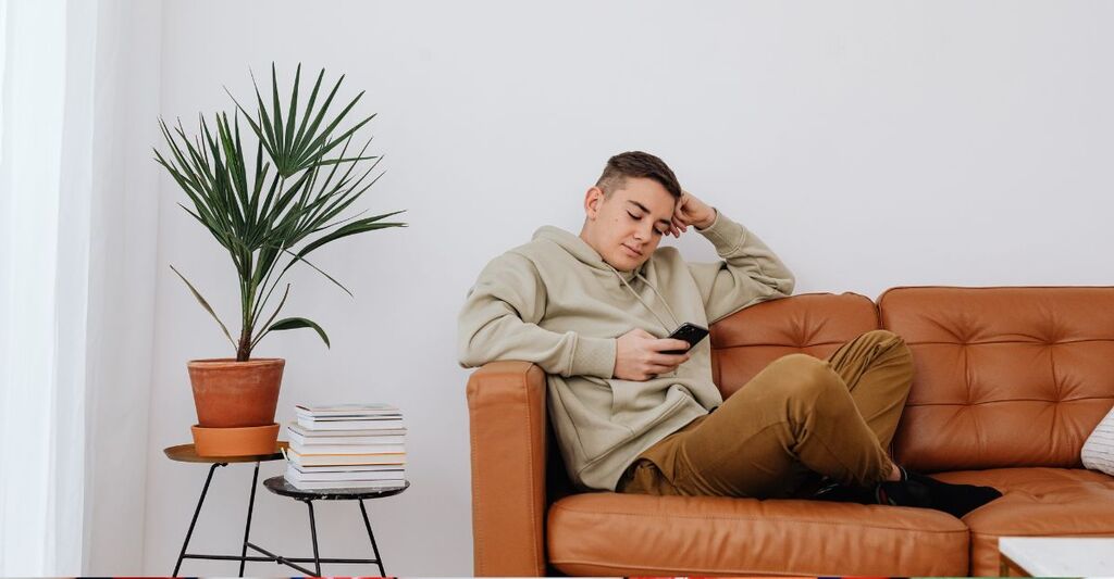 ragazzo sdraiato sul divano, guarda il cellulare