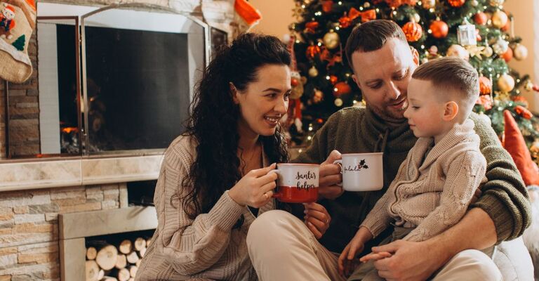 Famiglia che si gode bevande calde durante le vacanze di Natale a casa
