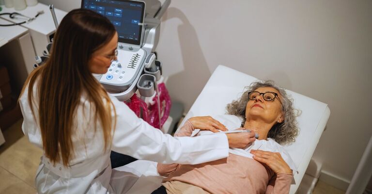 Medico che esegue un esame ecografico della tiroide su una paziente anziana