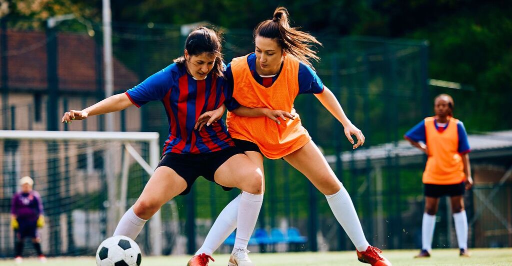 Giocatrici che placcano durante l'allenamento di calcio sul campo da gioco