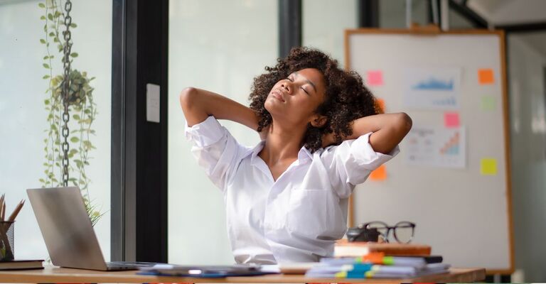 ragazza, seduta alla scrivania, fa stretching al collo