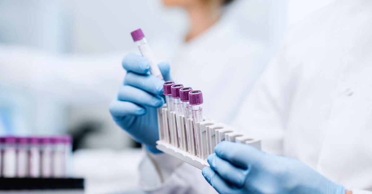 Assistente di laboratorio che inserisce le provette nel supporto, primo piano focalizzato sulle provette