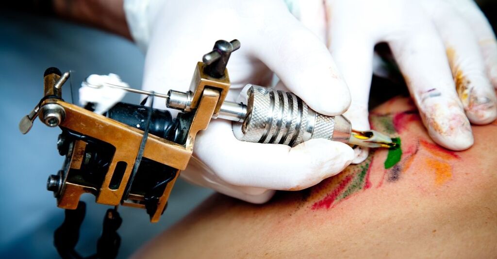 Un uomo fa tatuaggi con inchiostro rosso.