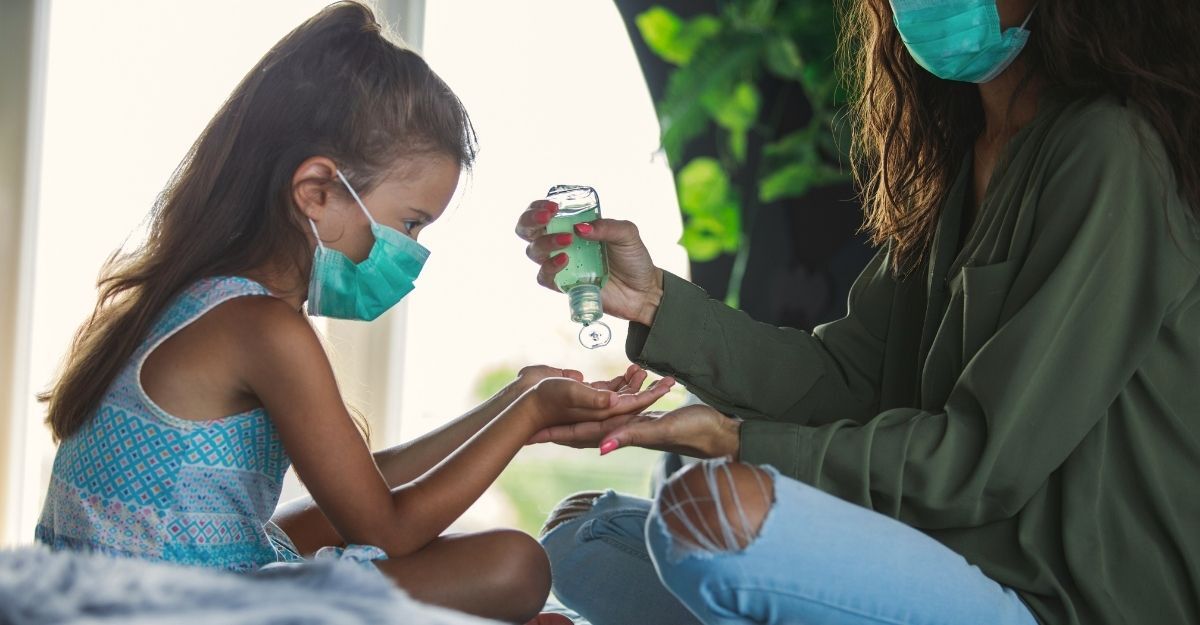 Una madre fa mettere il gel igienizzante mani alla figlia. Entrambe indossano la mascherina