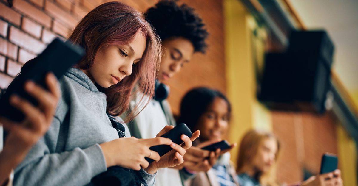 Un gruppo di adolescenti usa i cellulari nel corridoio di una scuola superiore