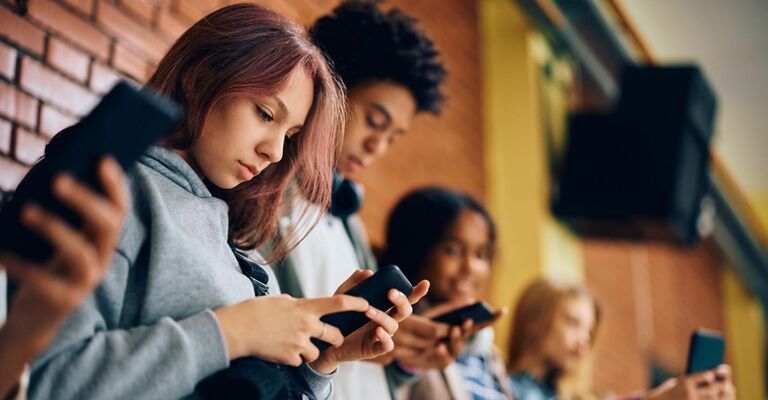 Un gruppo di adolescenti usa i cellulari nel corridoio di una scuola superiore