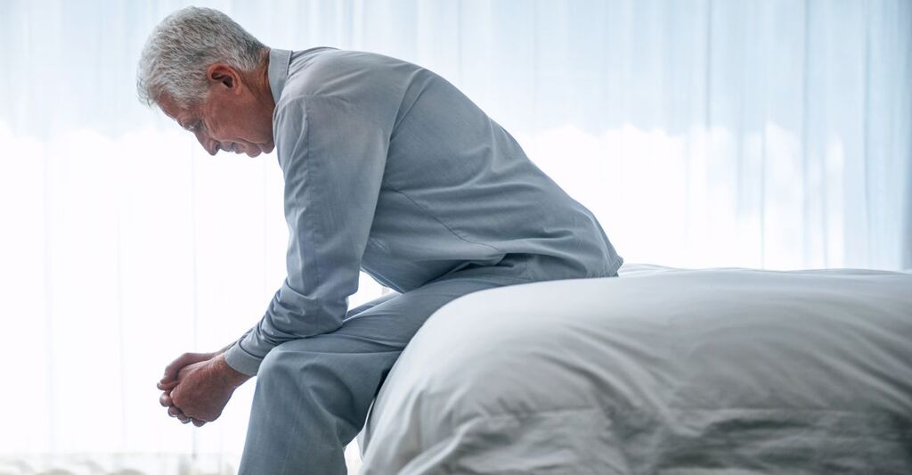 signore seduto sul letto, sembra riflettere