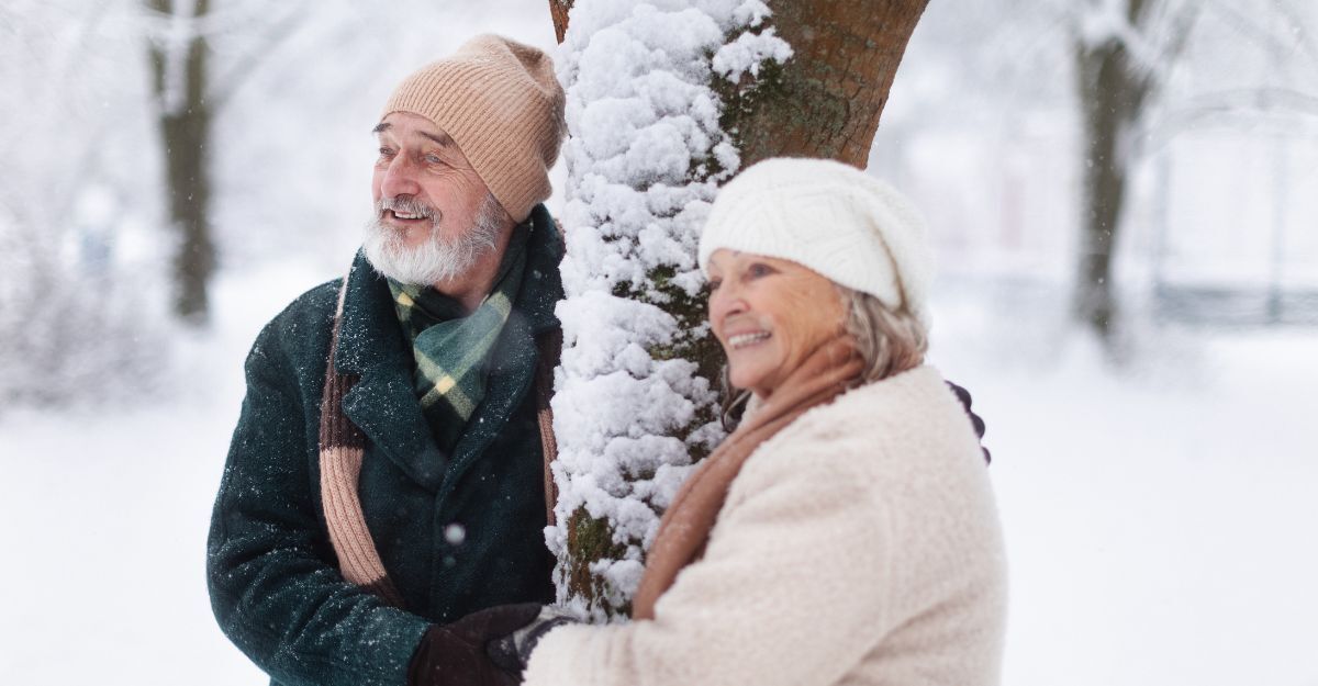 una coppia di anziani, vicino ad un albero coperto di neve
