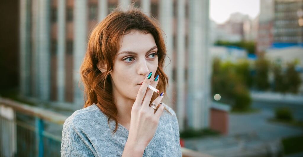 Ragazza con una sigaretta in mano che fuma per strada