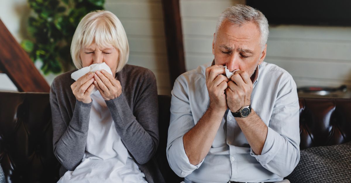 Concetto di virus e influenza. Una famiglia anziana seduta sul divano si soffia il naso. Una coppia malata cerca di starnutire nel tovagliolo. Hanno preso un raffreddore e ora devono prendere delle medicine per guarire.