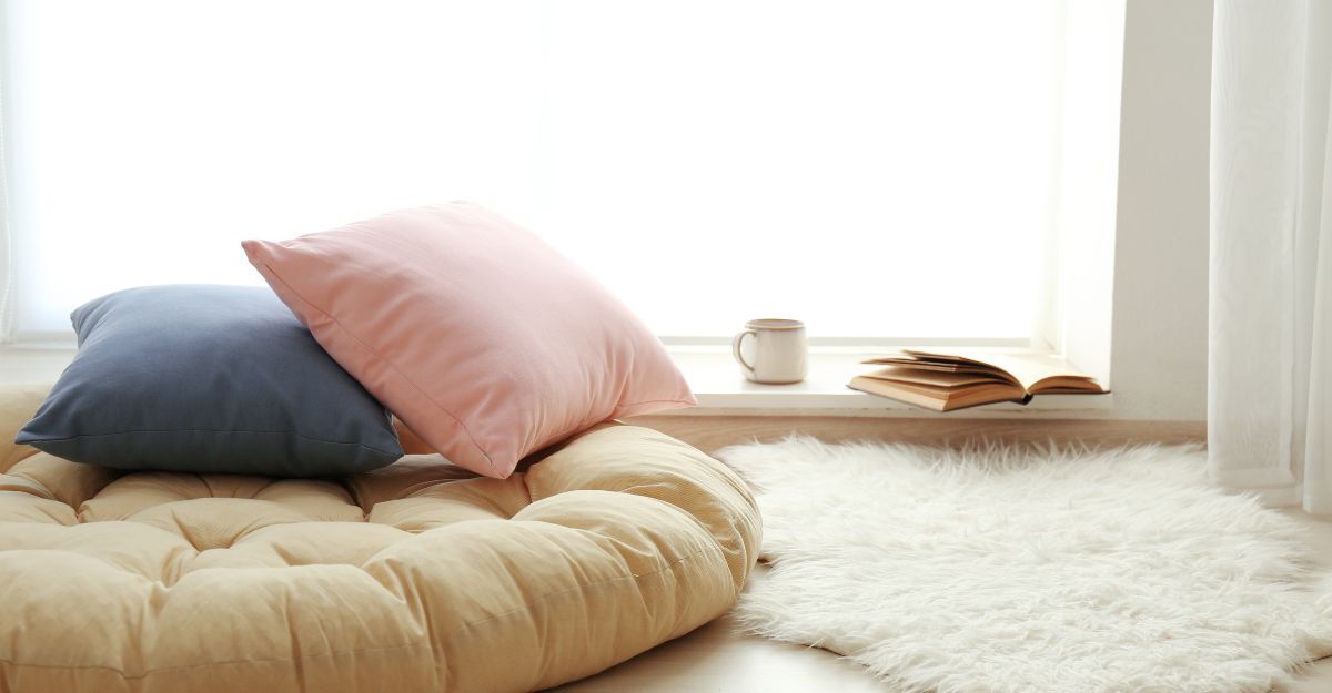 cuscini, tappeto peloso, un libro ed un tazza di te alla finestra