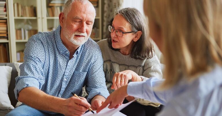 Un signore over 60 firma un documento per le DAT insieme alla moglie e un legale di riferimento