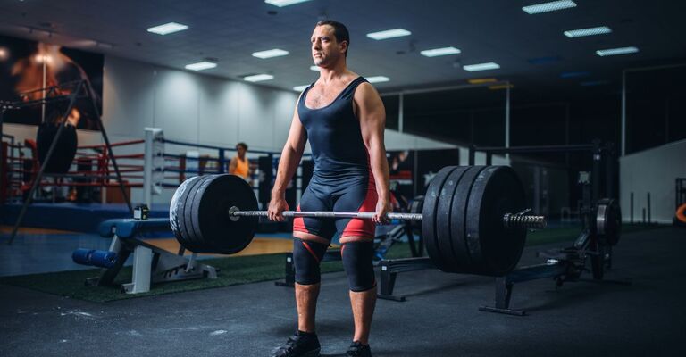 Un uomo in palestra si allena fino al dolore muscolare per far crescere i muscoli.