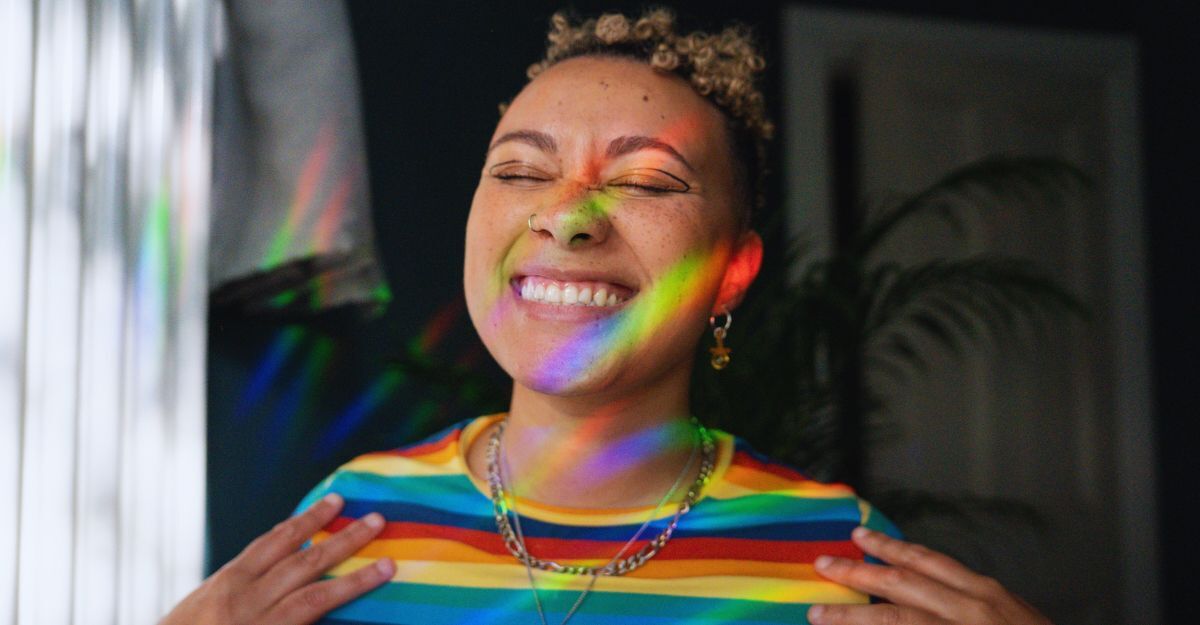 Ragazza in primo piano che sorride con gli occhi chiusi mentre la luce del sole scomposta in colori le arriva in faccia