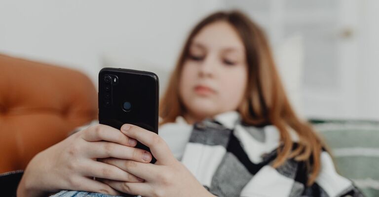 ragazza sdraiata sul divano guarda il cellulare