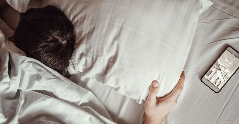 uomo dorme nel letto, con la testa appoggiata al cuscino