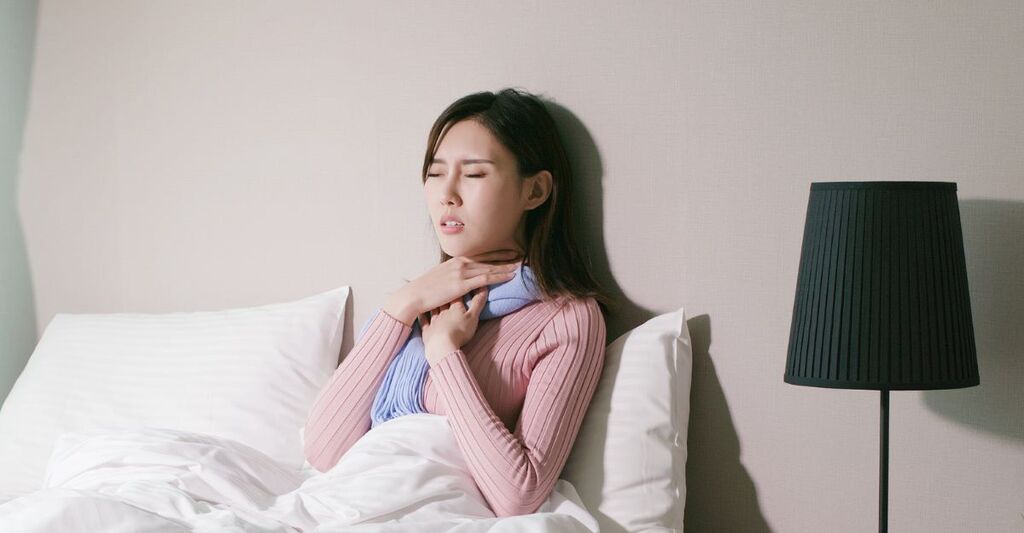 Una donna con mal di gola ricorrente a letto in camera.