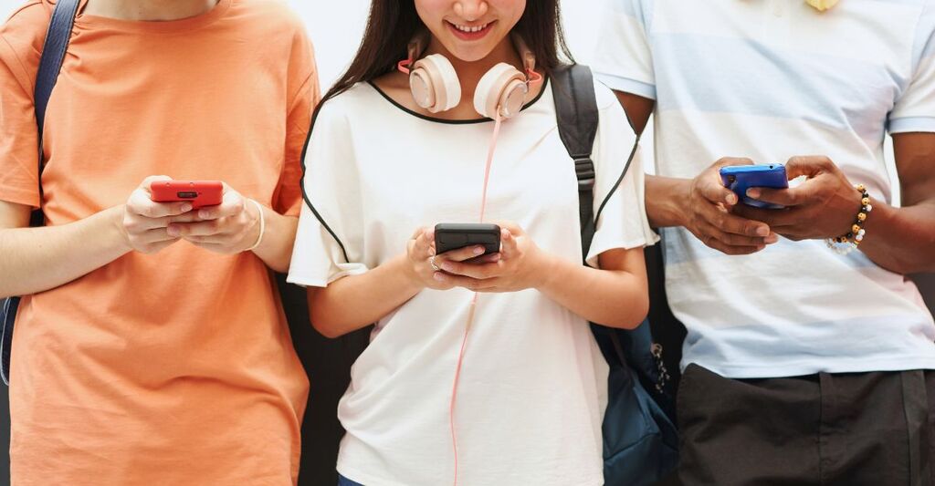 Tre giovani al telefono consultano l'intelligenza artificiale.