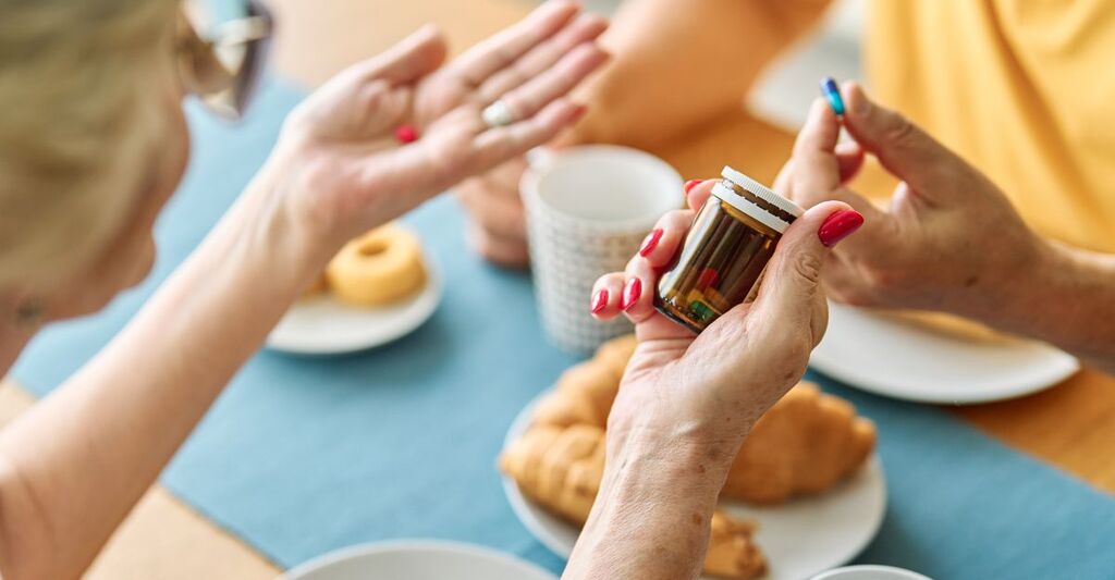Ritratto di una coppia di anziani, un uomo e una donna, che tengono in mano un farmaco o una prescrizione prima di prendere le pillole durante il pranzo a casa