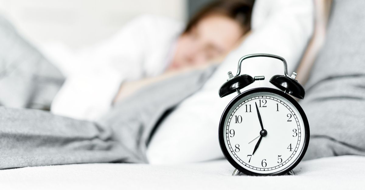 Il primo piano di una sveglia con una ragazza che dorme a letto