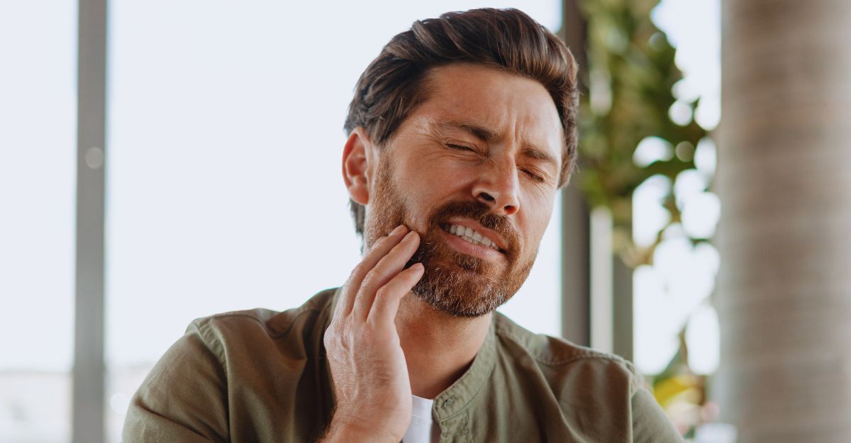 Uomo che soffre di forte mal di denti toccandosi la guancia