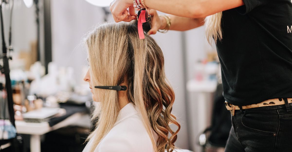 Una parrucchiera applica delle extension ai capelli biondi di una cliente in un salone di bellezza