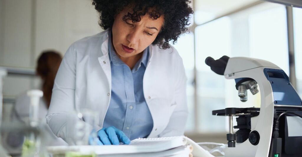 Una chimica fa delle ricerche mentre legge libri scientifici in laboratorio