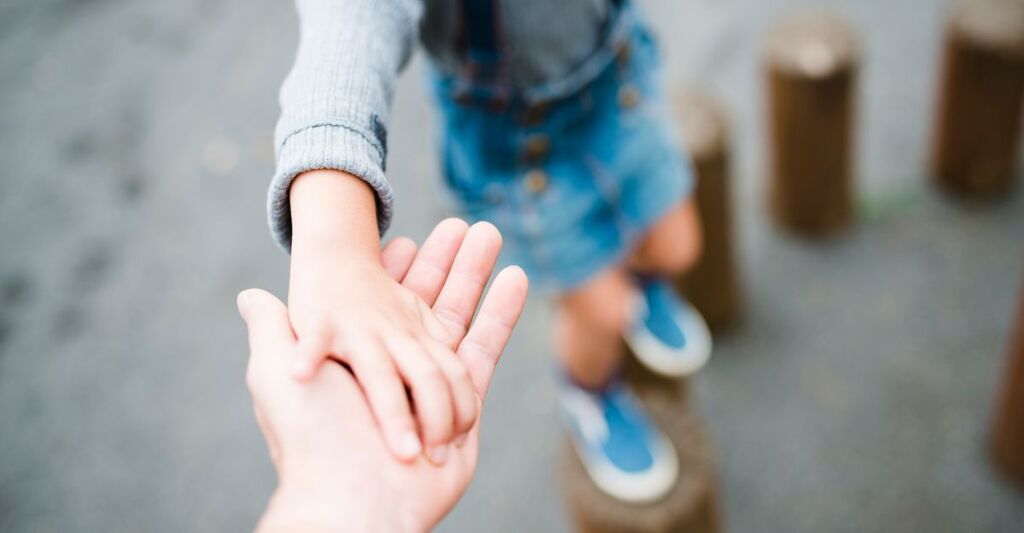 mano di adulto tiene la mano di un bambino