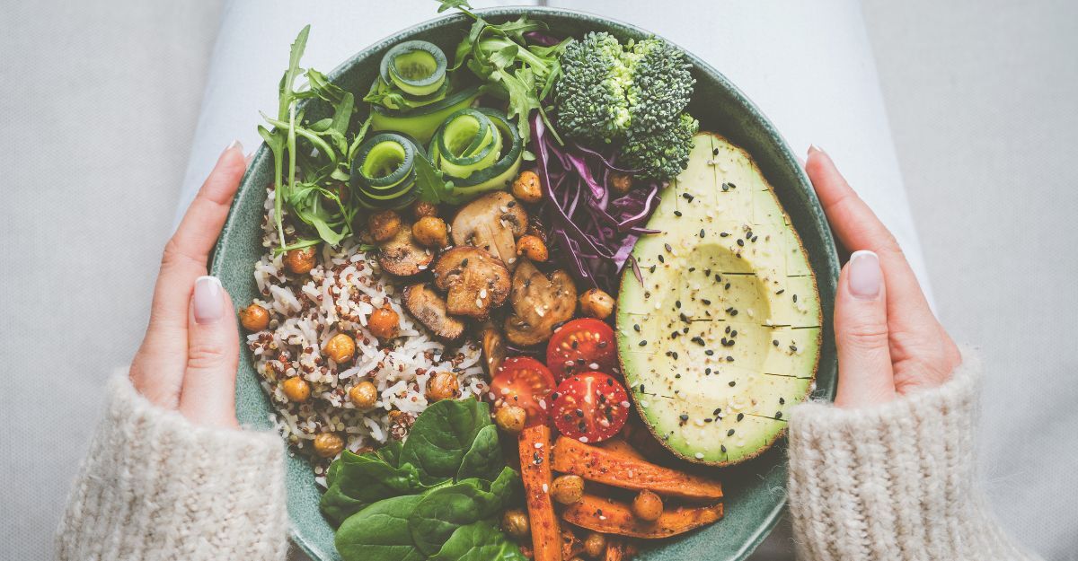 Donna che tiene in mano un piatto con cibo vegano o vegetariano. Dieta sana a base vegetale. Cena o pranzo sano. Ciotola Buddha con verdure fresche. Alimentazione sana.