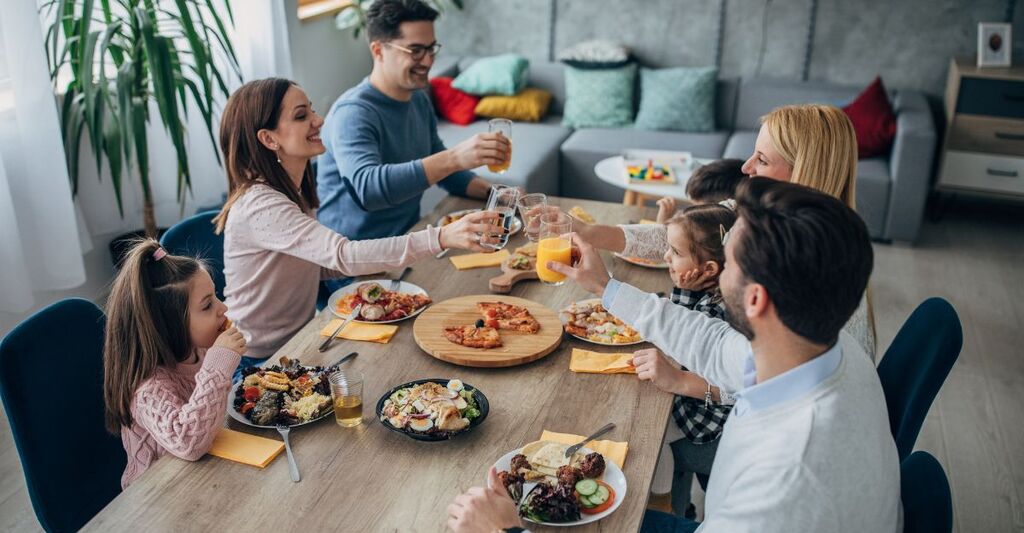 7 persone mangiano seduti al tavolo e brindano