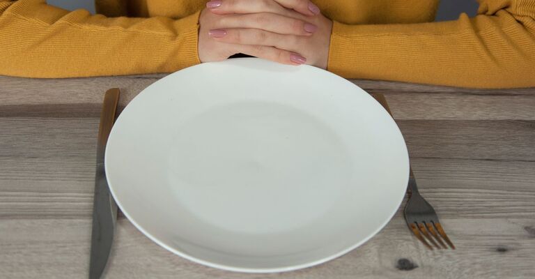 piatto vuoto e braccia di donna conserte