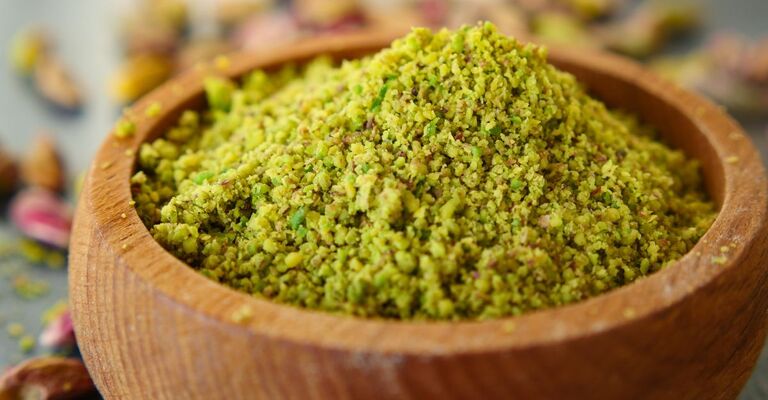 Ciotola di legno piena di farina di pistacchi, un superfood naturale e nutriente