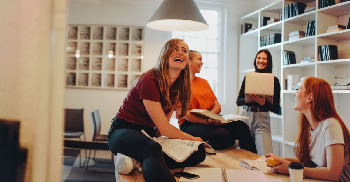 Un gruppo di giovani che ride e chiacchiera gioiosamente mentre studia insieme in una stanza luminosa