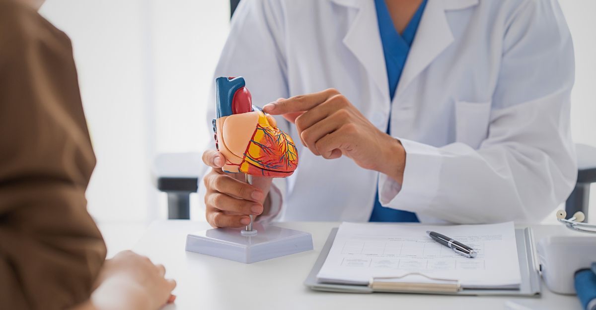 Un cardiologo con un modellino del cuore spiega le cardiopatie congenite a un paziente.