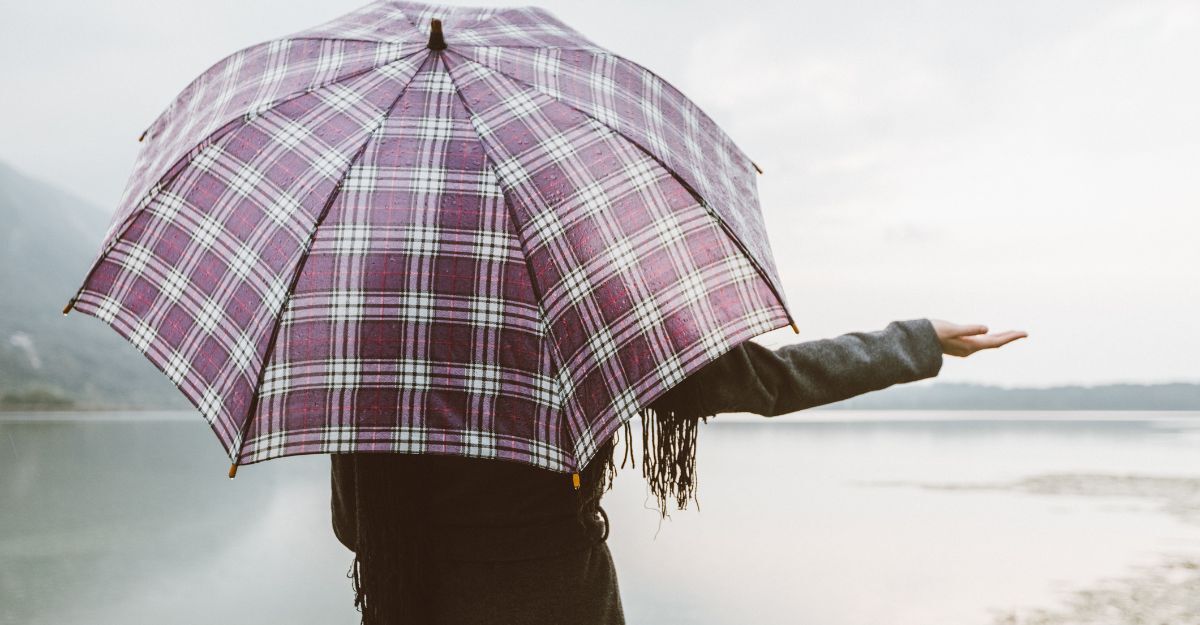 ragazza di spalle, con l'ombrello, allunga la mano per vedere se piove