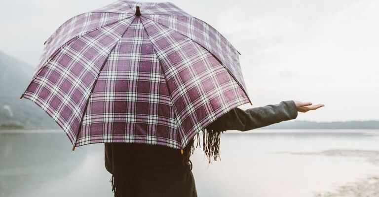 ragazza di spalle, con l'ombrello, allunga la mano per vedere se piove