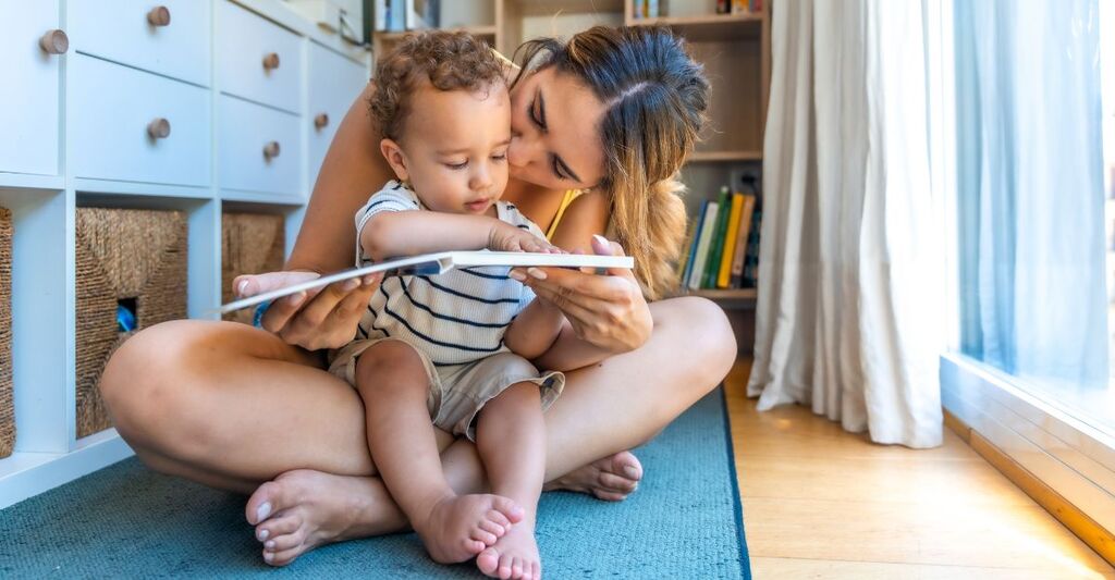 Madre amorevole che legge un libro con il suo adorabile figlioletto a casa