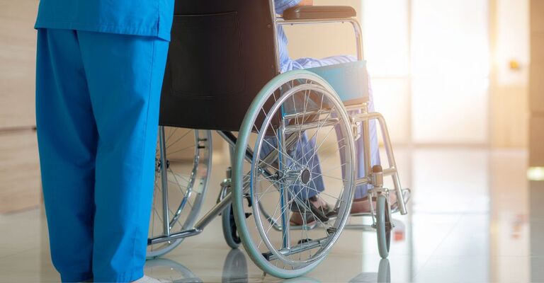 medico trasporta paziente sulla sedia a rotelle