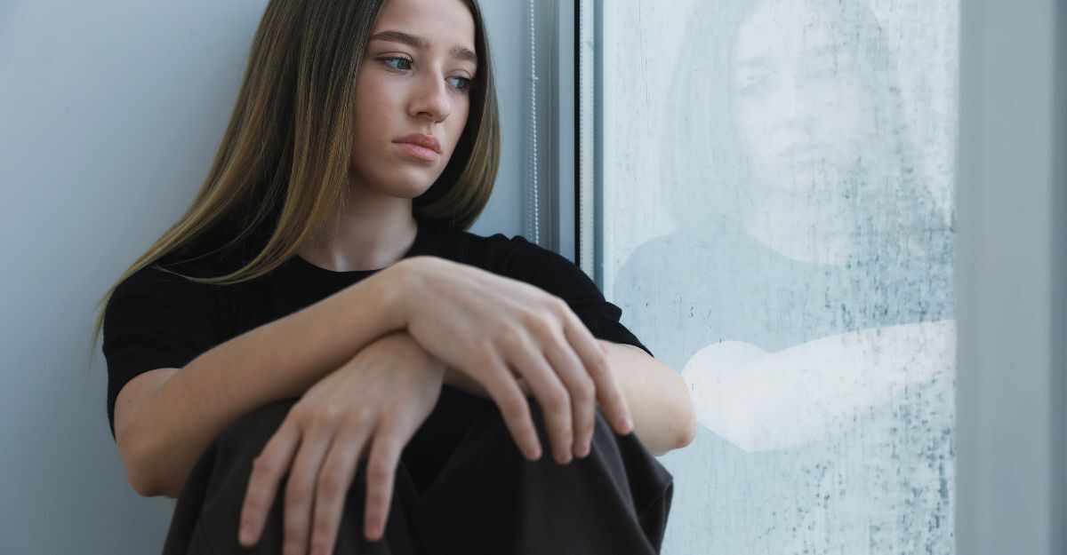 Una ragazza triste che guarda fuori dalla finestra
