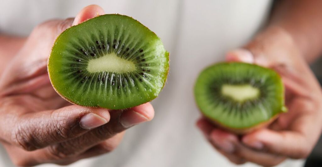Metà di kiwi appena tagliati tenuti in mano per l'esposizione
