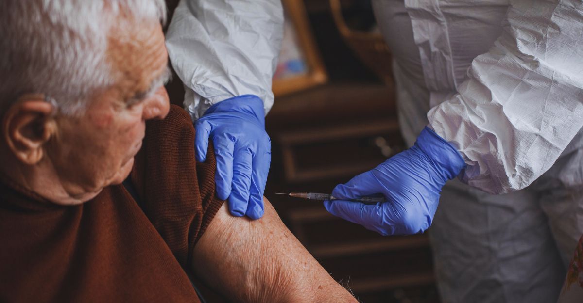Medico in tuta protettiva vaccina un anziano a casa durante un'epidemia