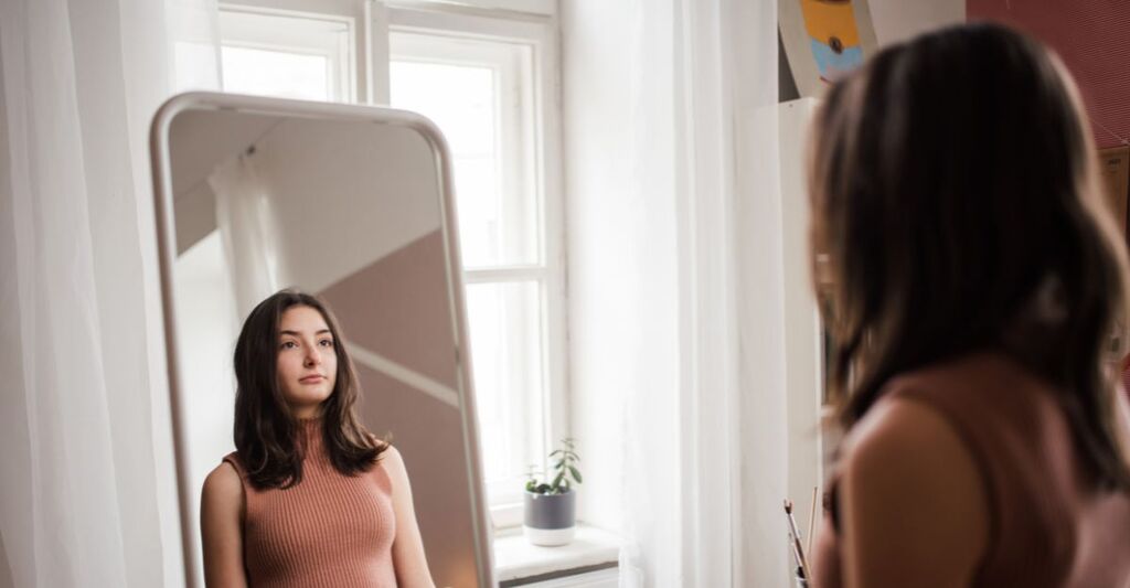 Una giovane adolescente si guarda allo specchio nella sua stanza