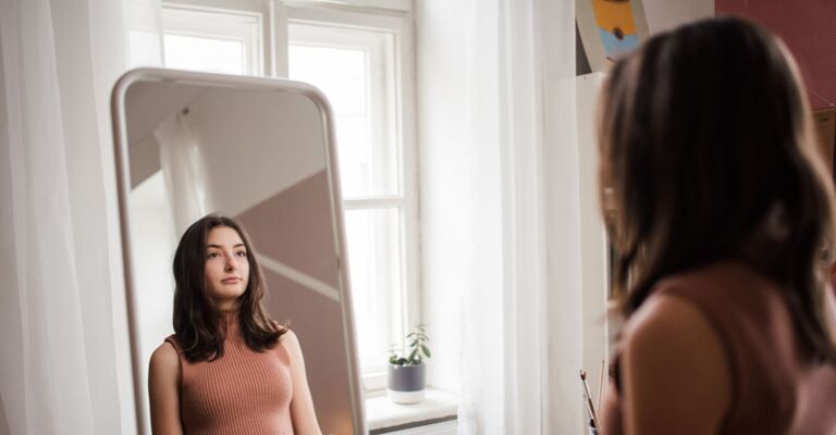 Una giovane adolescente si guarda allo specchio nella sua stanza