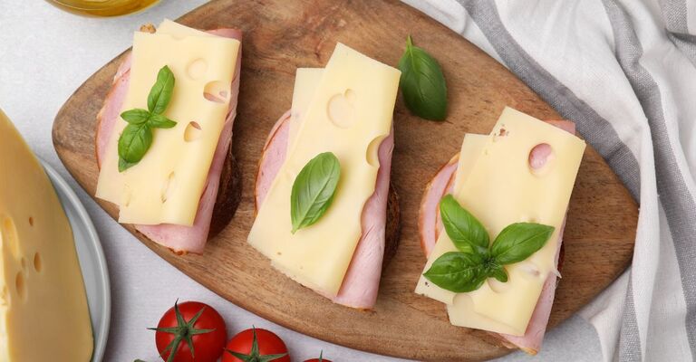 Deliziosi panini con prosciutto, formaggio e prodotti su un tavolo luminoso, distesi