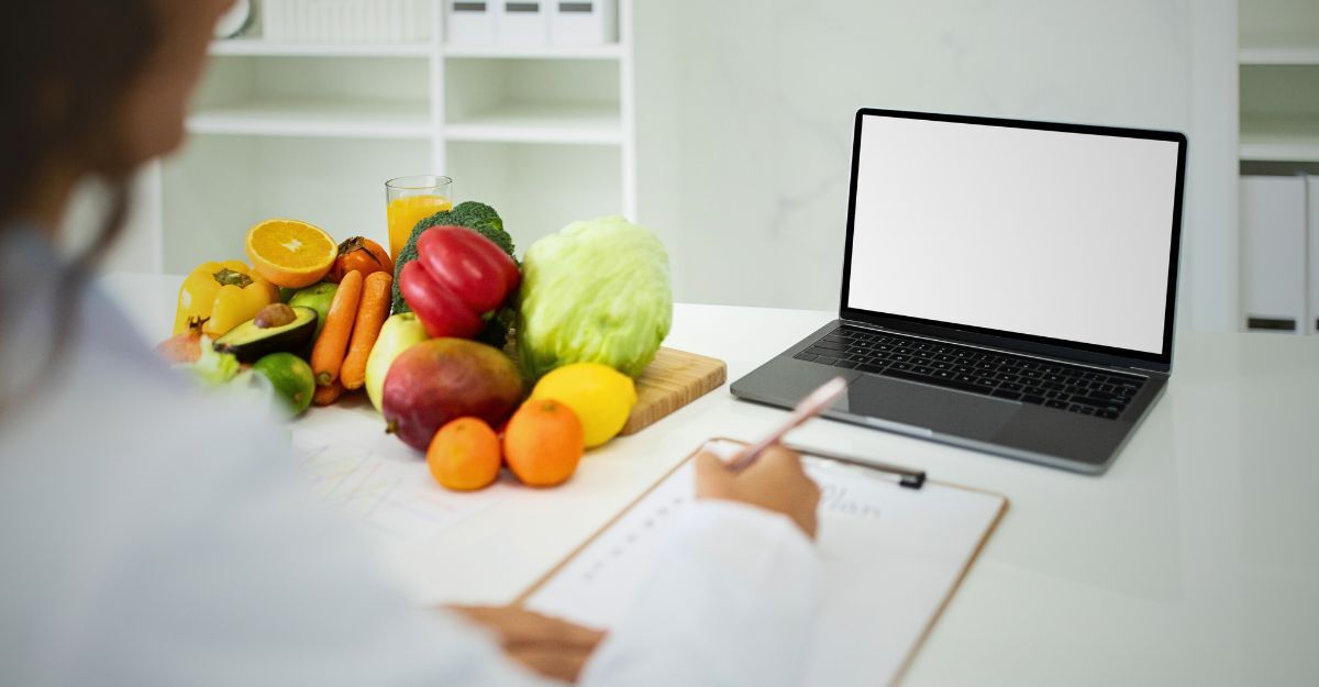 Una dietologa con frutta sul tavolo.